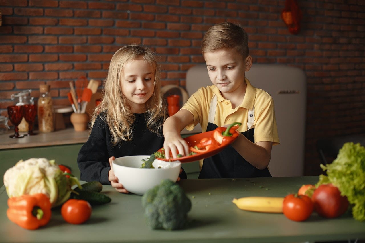 content-children-preparing-healthy-salad-together-in-loft-3984725